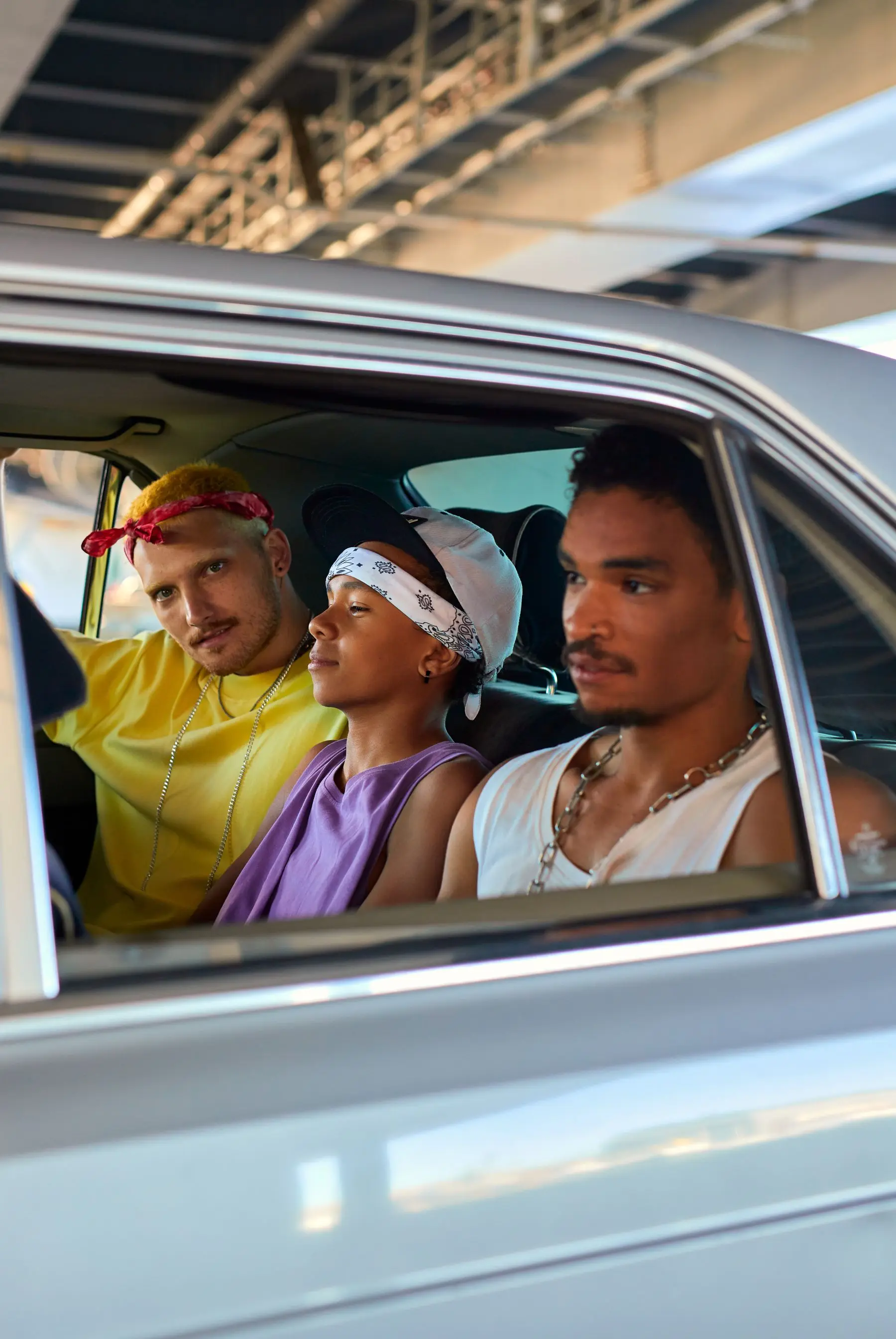 Three passengers sharing a car ride together, leaning out of the car window on a bright day